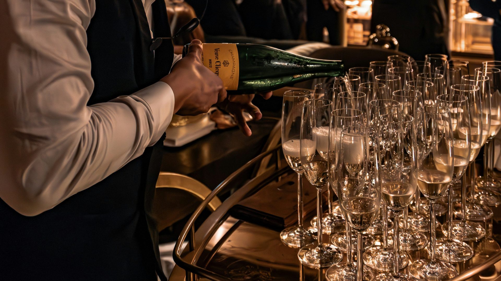 A bartender pours champagne into awaiting flutes.