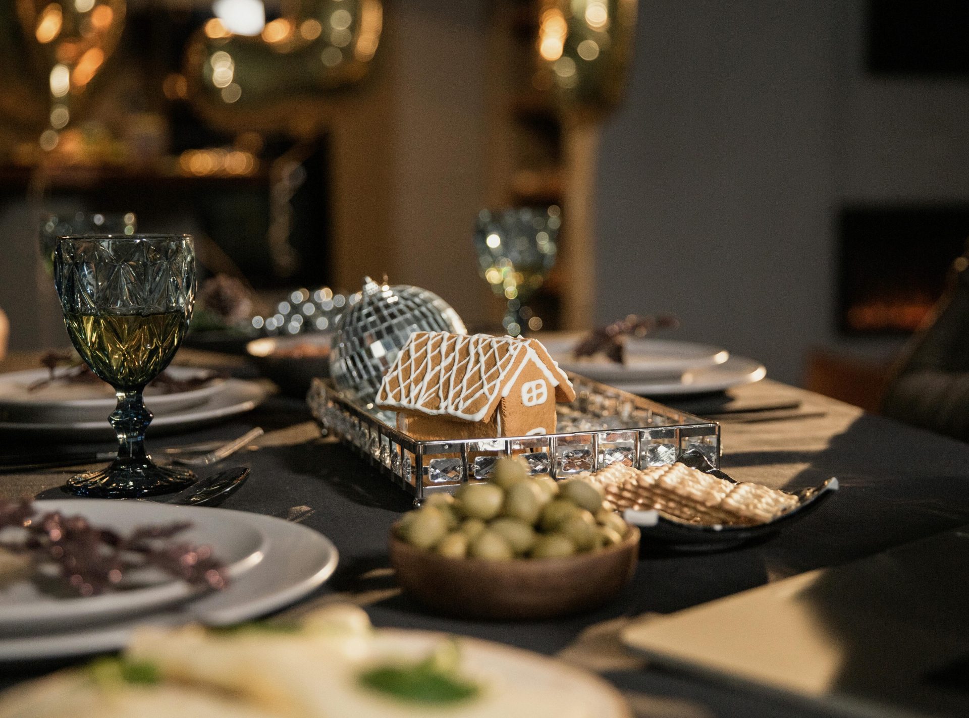 A beautifully set table with a gingerbread house decoration, perfect for a festive gathering in a cozy indoor setting.