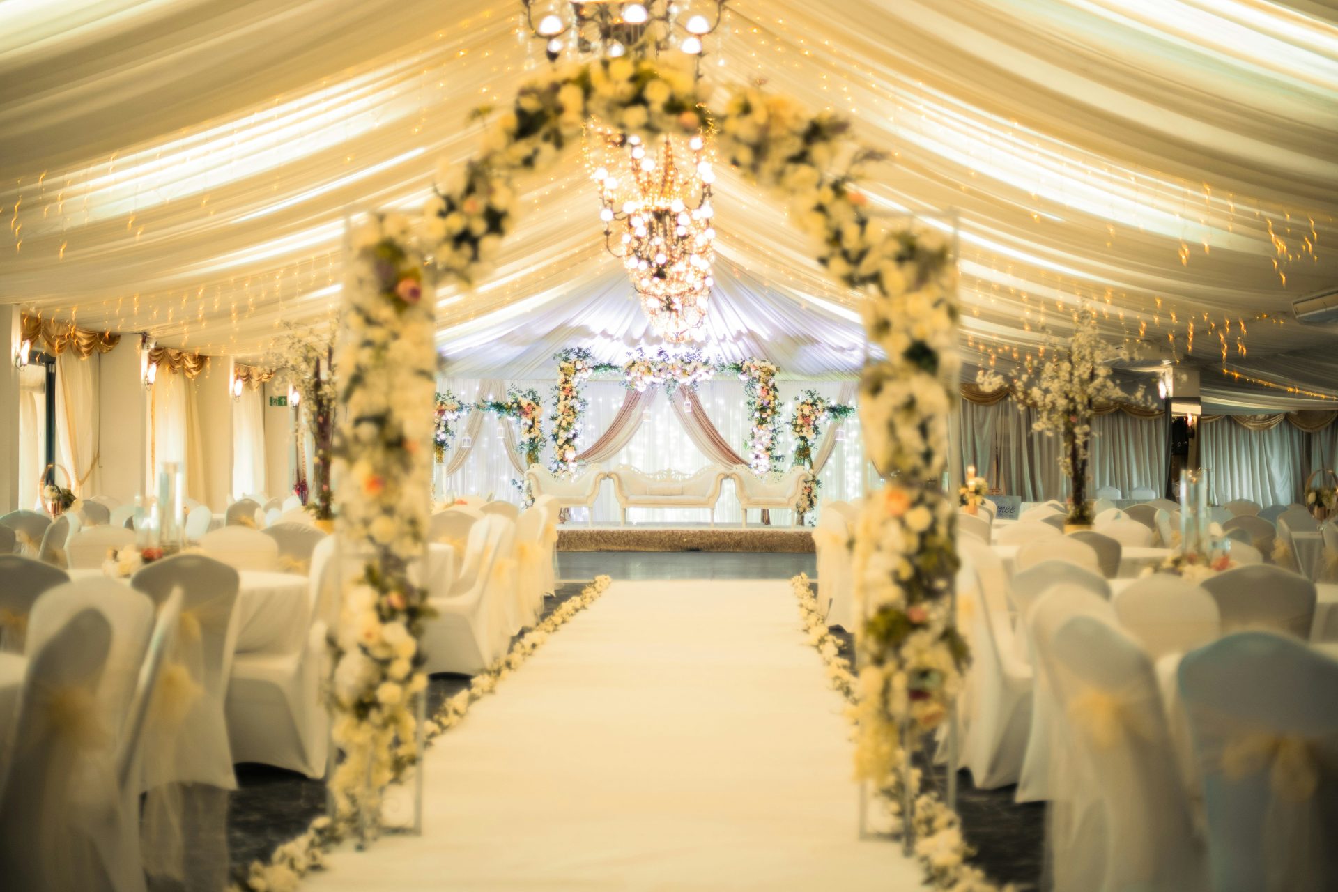 Elegant wedding reception hall with floral archway and white decor.